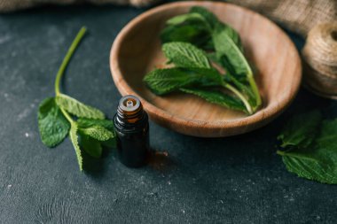 Ahşap zemin üzerinde nane olan bir şişe gerekli yağ..