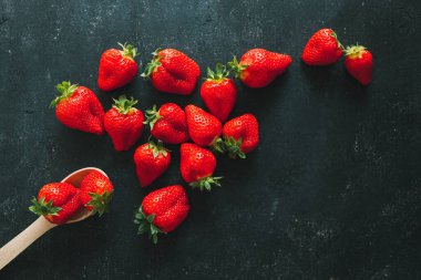 Olgun çilek yığını siyah ahşap arka planda fotokopi alanı ile. Üst görünüm.