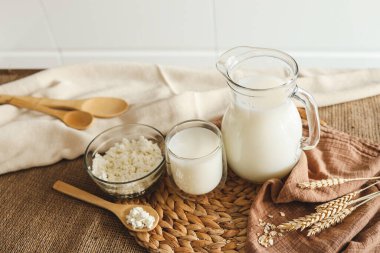 Süt sürahisi ve bir kase süzme peynir ahşap mutfak masasında..