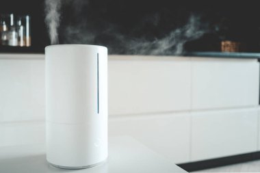 Aroma yağı yayıcı evdeki masada, hava nemlendiricisinden buhar çıkıyor..
