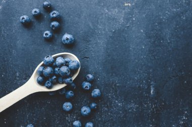 Tahta kaşıkta taze yaban mersini. Düz yatış, üst görünüm.