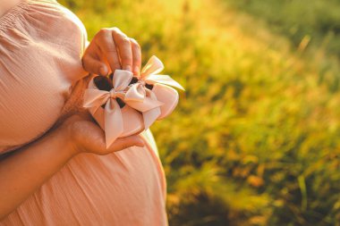 Hamile bir kadın elinde şirin bebek ayakkabıları tutuyor. Bebek beklemesi kavramı..