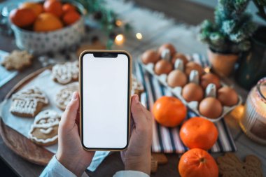 Noel yemeğinin arka planında boş ekranlı bir telefon. Mesaj için yer. Ana sınıf davetiyesi. Mutlu Noeller.