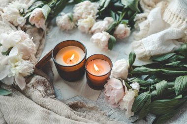 Sıcak bir evde yanan iki mum, beyaz şakayıklar ve badem kurabiyeleri..