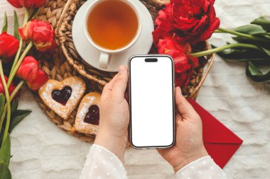 Şenlikli bir arka planda cep telefonu ve bahar çiçeği laleleri. Aşk teması, Anneler Günü, Kadınlar Günü düzlük.