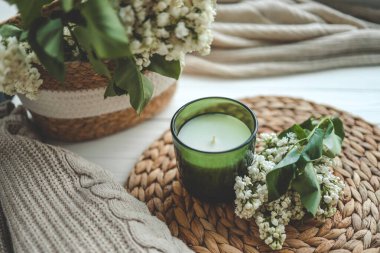 Yeşil bir kavanozda mum, açık bir kitap ve bir buket beyaz leylak, bahar içleri..