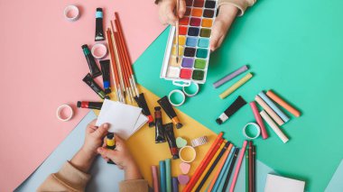 Okula dönelim. Panoramik eğitim afişi. Üst manzara, düz yatış. Masada renkli malzemeler, renkli kağıtlar. Çocukların yaratıcılık kavramı. Anaokulu eğitimi, gelişme. Okul için aksesuarlar..