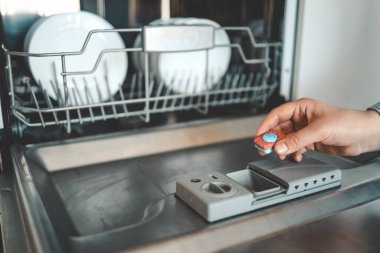 Bulaşık makinesi kapsülü, bulaşık makinesi tableti kadın kapsülü bulaşık makinesine koydu..