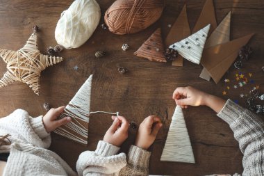 Çocuklar iplikten Noel süslemeleri yapıyorlar.