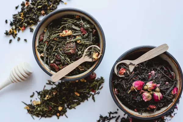 Beyaz arka planda bitki ve çiçek çayı ile tabaklar.