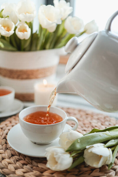 Tea pouring into cup from teapot.