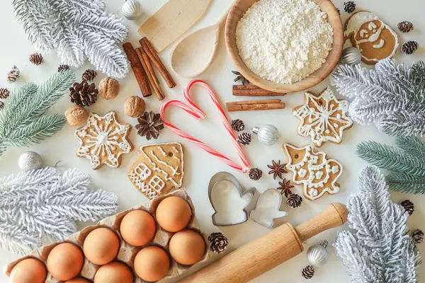 Pastanenin arka planında Noel pişirmek için malzemeler var. Masanın üstünde un, yumurta, tarçın ve zencefilli ekmek..