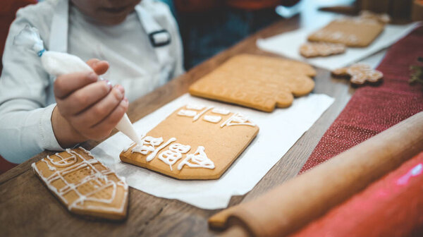 Дети украшают пряничный домик, уютная домашняя атмосфера Рождества.