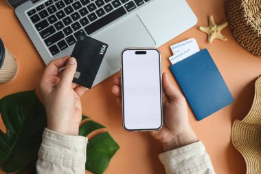 Kredi kartı ve akıllı telefon tutan kadın online uçak bileti satın alma, üst görünümü.