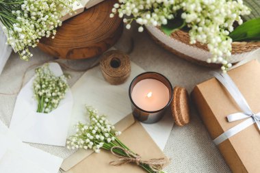 Kutlama konsepti, vadideki zambak, hediye kutusu, yanan mum ve mektup..