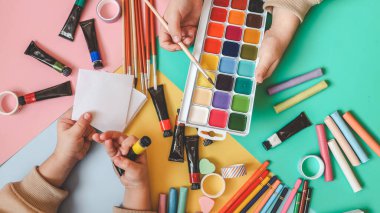 Okula dönelim. Panoramik eğitim afişi. Üst manzara, düz yatış. Masada renkli malzemeler, renkli kağıtlar. Çocukların yaratıcılık kavramı. Anaokulu eğitimi, gelişme. Okul için aksesuarlar..