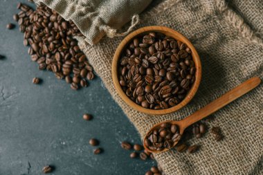 Coffee beans in a wooden plate on a black background.