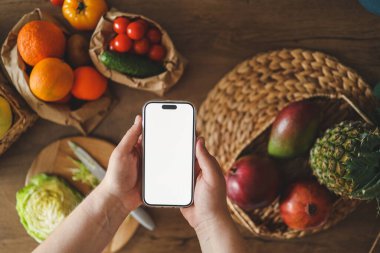 Mutfağın arka planında izole bir ekran bulunan telefon, kalori sayma konsepti ve uygun beslenme.