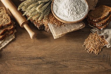 Ekmek, tahıl, buğday ve un başakları ahşap bir arka planda, fırın reklam afişi