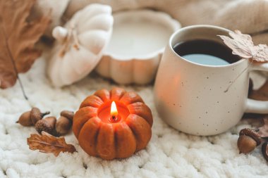 Balkabağı şeklinde yanan mum ve bir fincan çay, sonbahar havası..