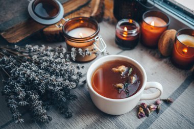 Bir fincan bitki çayı, yanan mumlar, estetik olarak sıcak bir fotoğraf..