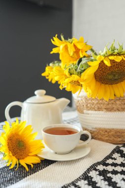 A cup of tea and a teapot with a candle on a table with sunflowers, tea time, aesthetics