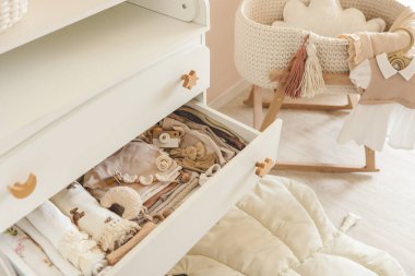 Yeni doğanlar için komodinin yanında iç mekan ve bebek eşyaları var..