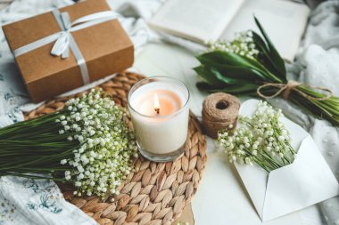 Beyaz, yanan bir mum ve bir buket vadi zambağı, doğal bir bahar fotoğrafı..