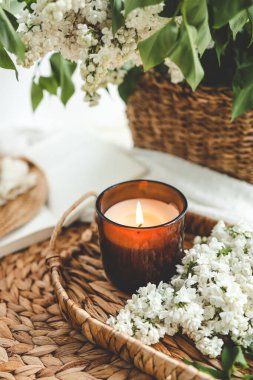 Evin içinde yanan mum ve beyaz leylak sepeti..