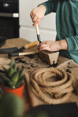 Küçük çocuk bahçeyle uğraşıyor..