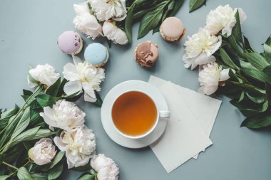 Bir fincan çay, badem kurabiyesi ve şakayık, düz bir manzara. Günaydın konsept.