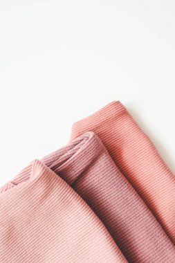 Beyaz arka planda pembe bebek kıyafetleri yığını.