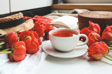 Güzel bahar kompozisyonu, günaydın konsepti. Bir fincan çay, şakayık, açık kitap..