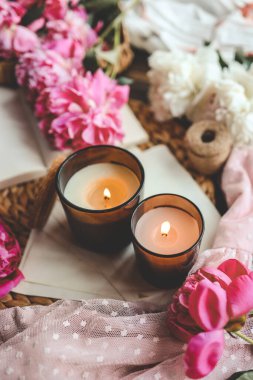 İki yanan mum ve pembe şakayık, bahar atmosferi..
