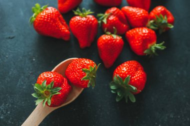 Olgun çilek yığını siyah ahşap arka planda fotokopi alanı ile. Üst görünüm.
