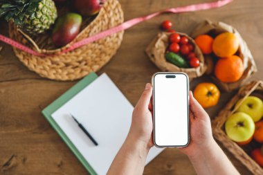 Mutfağın arka planında izole bir ekran bulunan telefon, kalori sayma konsepti ve uygun beslenme.