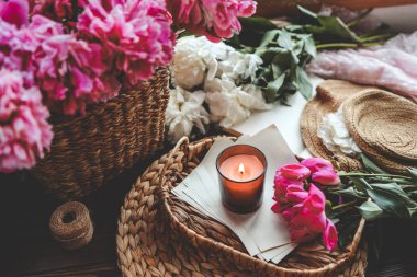 Sıcak bahar kompozisyonu, yanan mum, şakayıklar ve şapka..