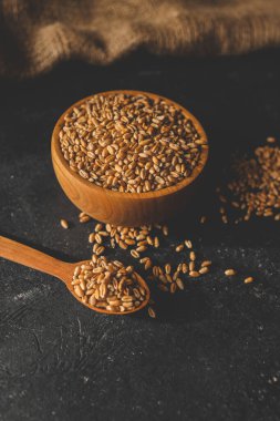 Koyu arkaplanda tahta bir tabakta buğday taneleri.