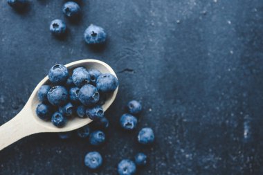 Tahta kaşıkta taze yaban mersini. Düz yatış, üst görünüm.