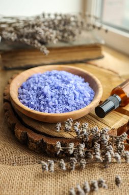 Eski ahşap bir masada mumlu mor banyo tuzu tabağı..