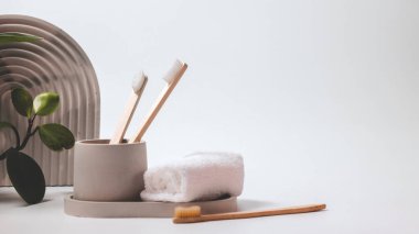 Bambu diş fırçaları beyaz arka planda zarif beton bir camda..