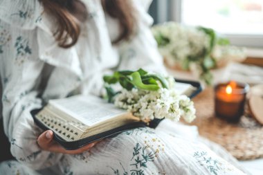 İncil okuyan kız, açık kitap ve leylak dalı, samimi bir fotoğraf..