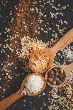 Siyah arka planda farklı baharatlı ahşap kaşıklar, afiş..