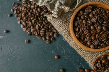 Coffee beans in a wooden plate on a black background.