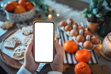Noel yemeğinin arka planında boş ekranlı bir telefon. Mesaj için yer. Ana sınıf davetiyesi. Mutlu Noeller.