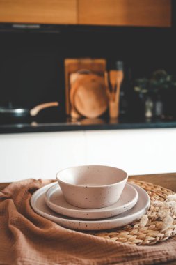 Mutfağın arka planındaki masada bej rengi minimalist tabaklar..