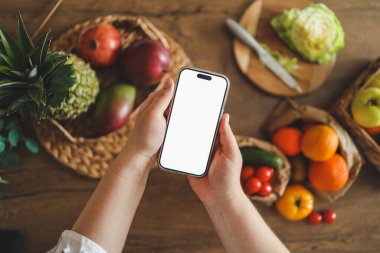 Mutfağın arka planında izole bir ekran bulunan telefon, kalori sayma konsepti ve uygun beslenme.
