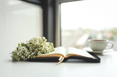 Çiçekli incili aç ve beyaz arka planda bir fincan çay..