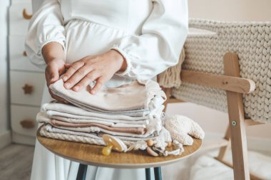 Hamile kadın doğumevi için hazırlanıyor, bebek eşyaları topluyor. Hamile kadın bebek kıyafetleri hazırlıyor ve planlıyor..
