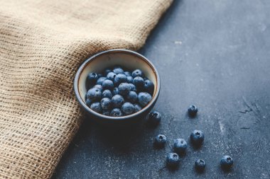 Fresh juicy blueberries in plates on a dark background top view.